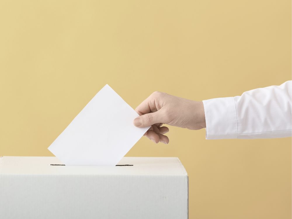 A person submitting their ballot to a ballot box for elections.
