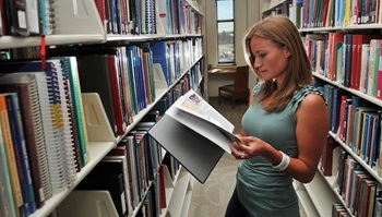 Student leafing through educational materials in library