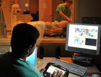 Healthcare professional interacting with computers while another interacts with a patient