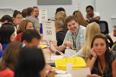 Multiple teams talking around long tables