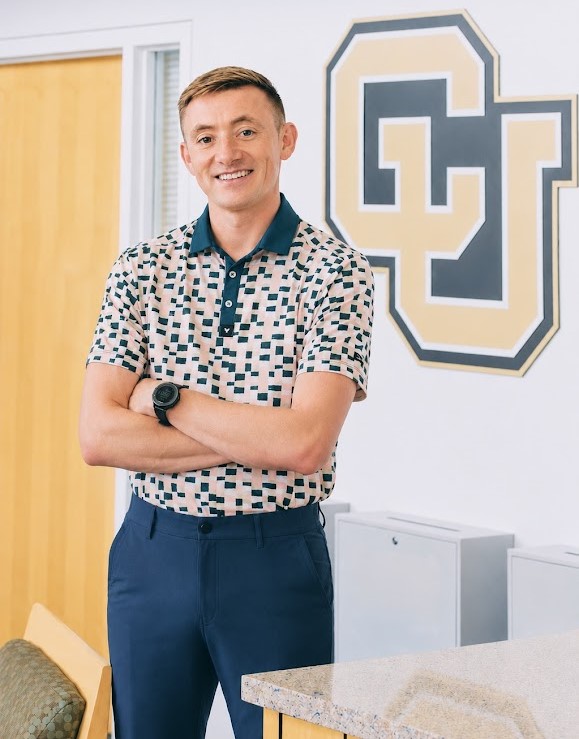 Jake Lueders, Assistant Director - white, male, brown hair, blue plants, checkered polo
