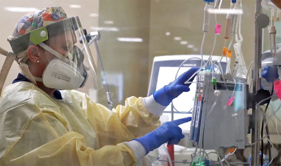 Registered nurse Gail Balbier adjusts a patient’s IV pump inside ICU at UCHealth