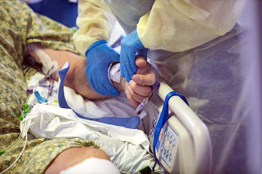 RN holds hand of COVID patient at St. Luke's Boise Medical Center