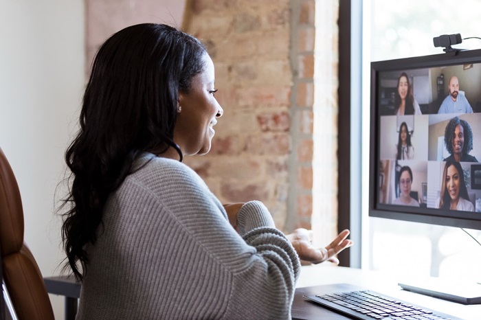 Woman participating in a virtual meeting at a desk.