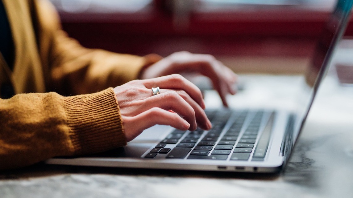 Hands typing on laptop