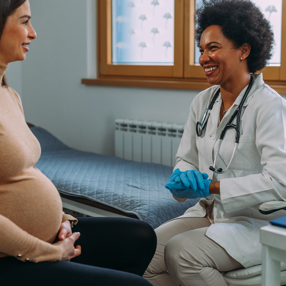 A pregnant women talking with her doctor, both are smiling