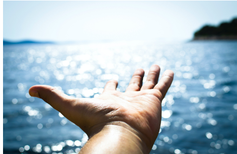 Outstretched hand by ocean