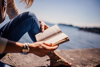 Person reading a book by the ocean Person reading a book by the ocean