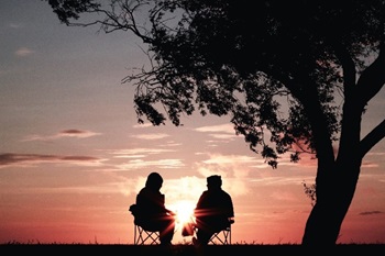Two people silhouetted by sunset