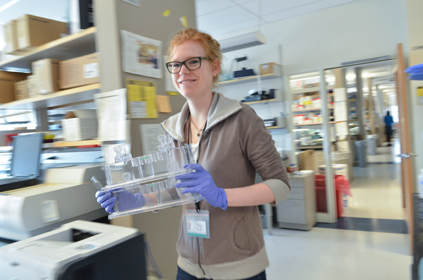 Scientist walking carrying test tubes