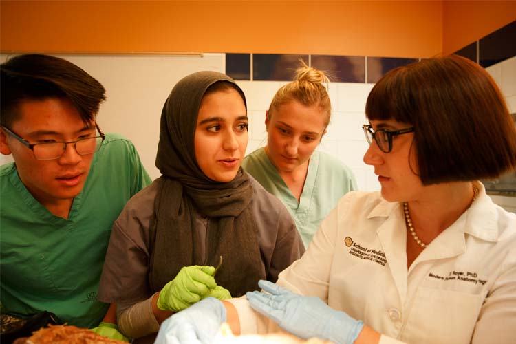 Three students learning from a professor