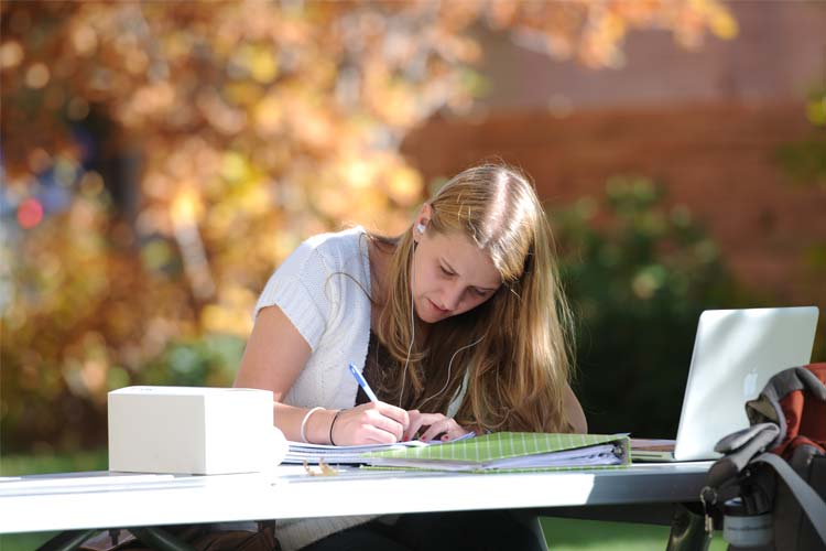 a student writing outside on a table