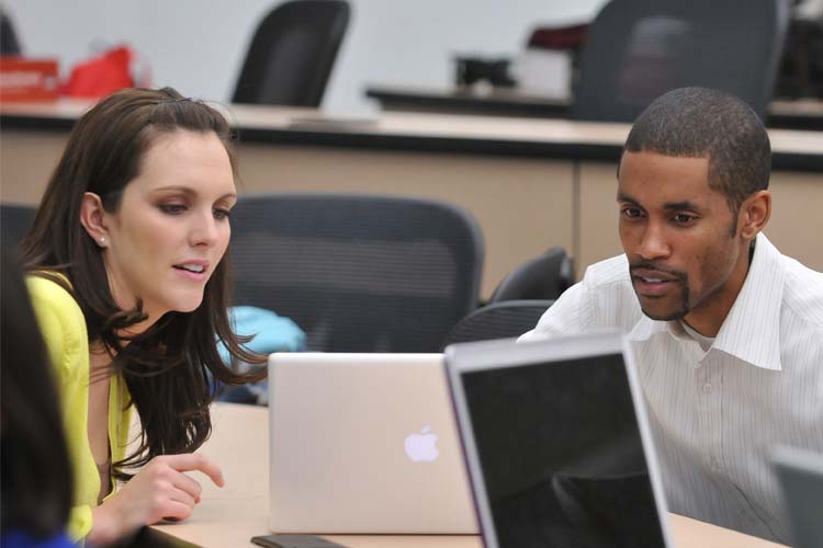 two students working together on a laptop