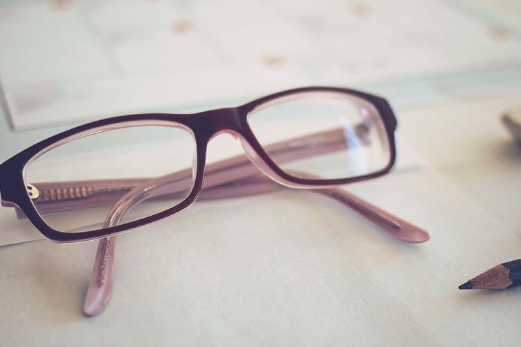 Eyeglass next to a pencil