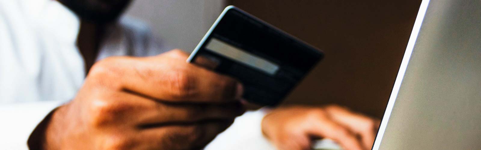 A person making a payment with their credit card on a laptop.