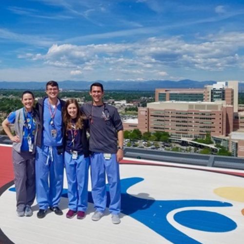 Pediatric residents in scrubs posing for group shot on the Children's Hospital helicopter landing pad.