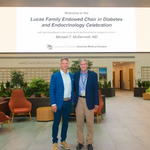 SOC Article Feature Image Lucas Endowed Chair Benefactor and faculty stand in front of the jumbotron on the Health Sciences Building promoting the establishment of the new endowed chair.