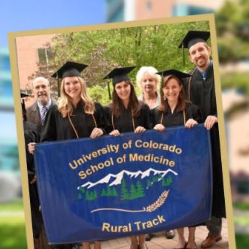 Graduating students in commencement attire hold up a 'University of Colorado School of Medicine Rural Track' banner.
