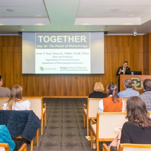 Dean Tsuji saying a few words during the 2026 Power of Philanthropy celebration with a projected slide behind him that reads, 