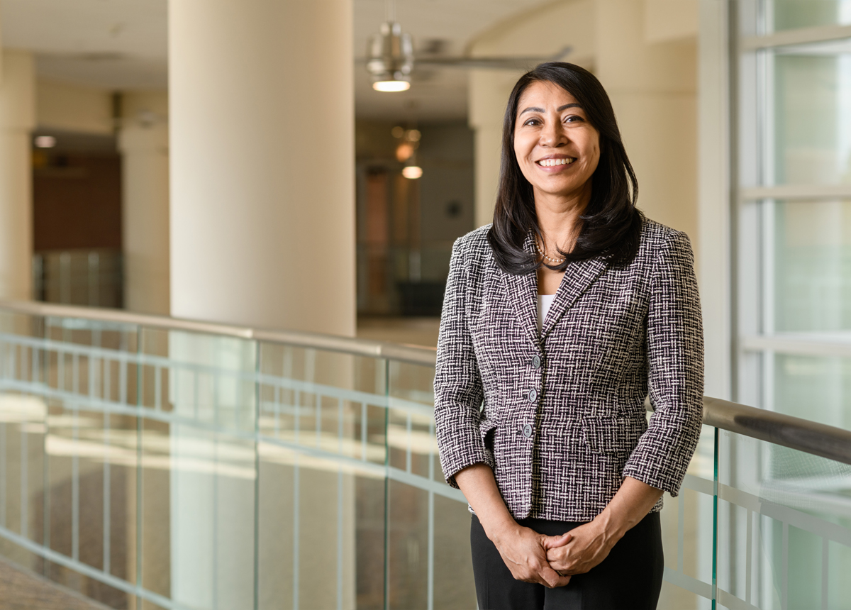 A photo of Dr. Borrayo smiling. She is wearing a gray and white patterned blazer.