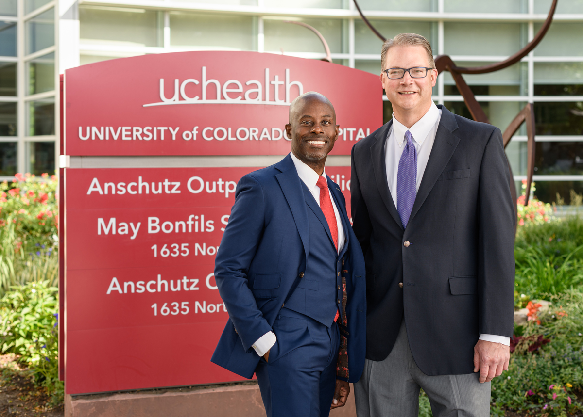 Dr. Reed and Dr. Wells stand in front of the UCHealth Anschutz Outpatient Pavilion sign.