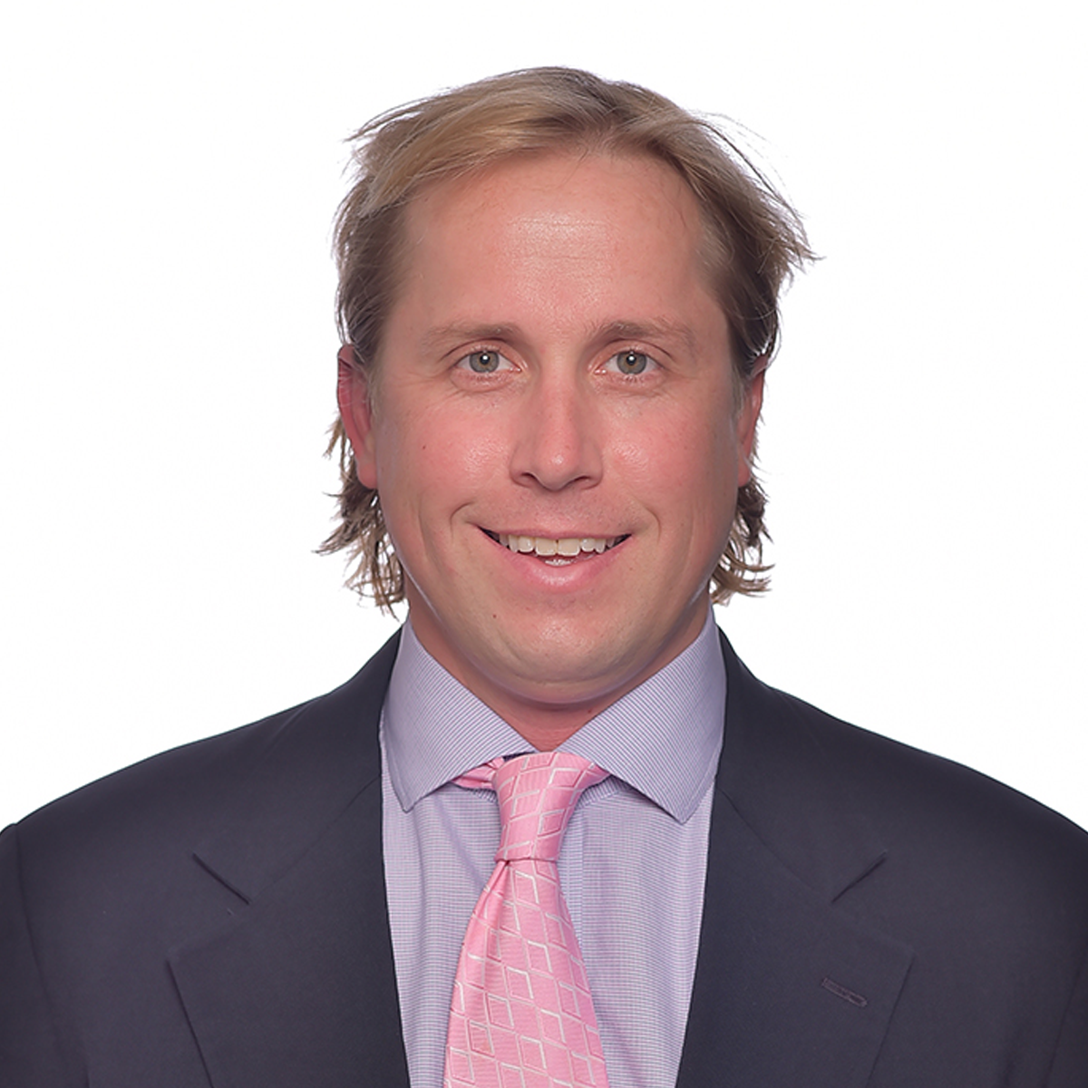 Daniel Owens, medical scholar. He is wearing a light purple shirt and a pink tie with a dark blazer, and is smiling at the camera.