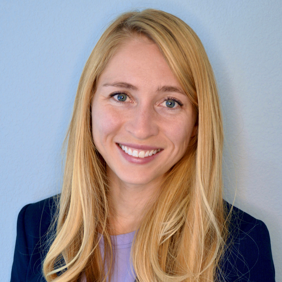 Emily Wolverton, smiling at the camera. She is wearing a light purple t-shirt and a dark blue blazer.