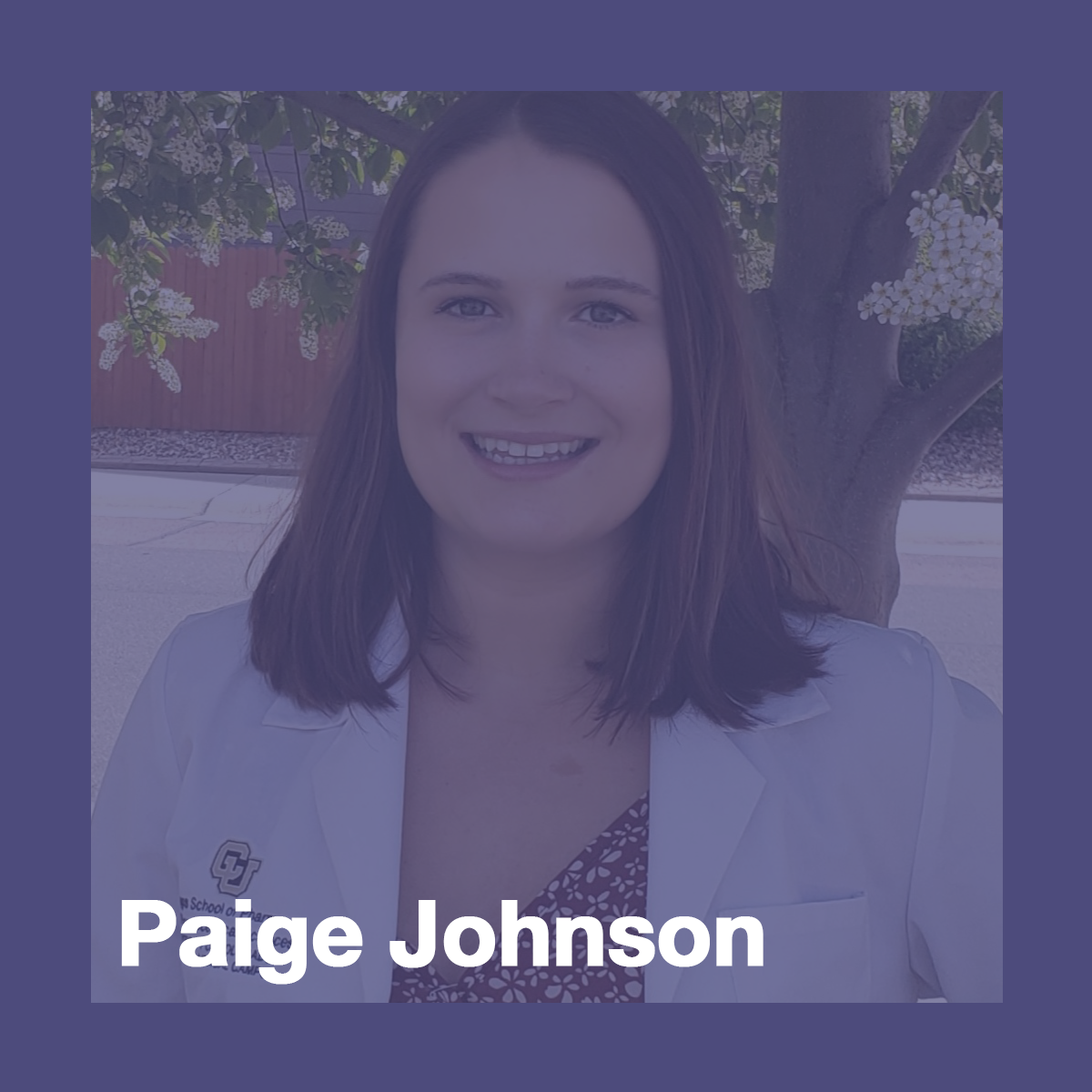 Paige Johnson, pharmacy scholar. She is smiling at the camera. She is wearing a white pharmacy coat over a maroon shirt and standing in front of a small tree and a street.