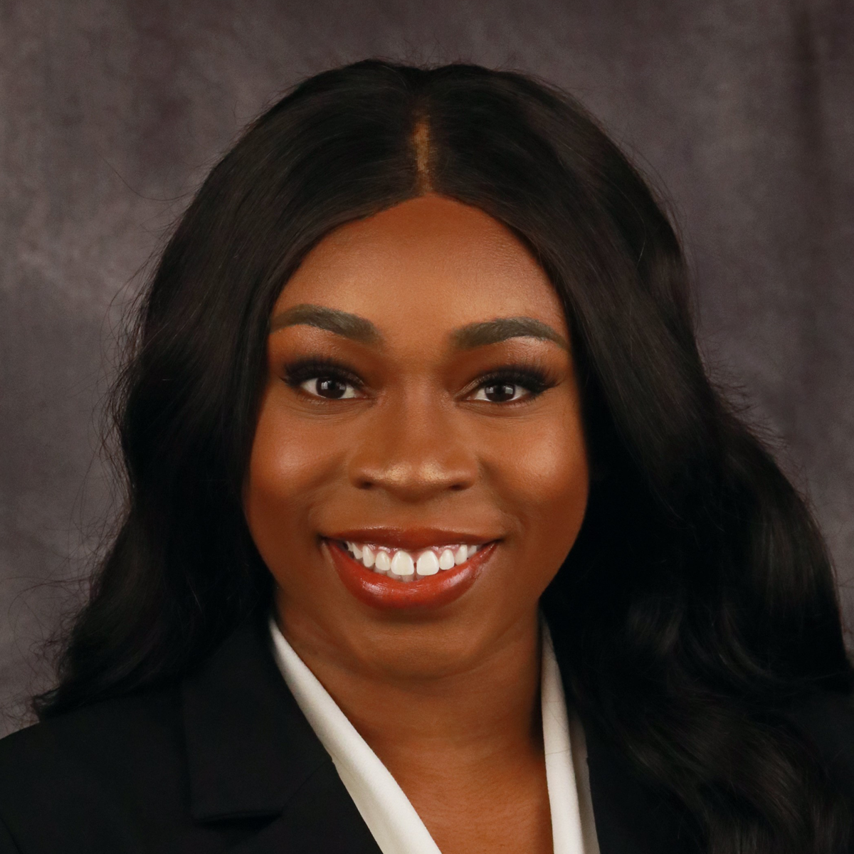 Stephanie Nwagwu, medical scholar. She is smiling at the camera. She is in front of a gray photo-studio background.