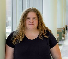 Dionisia for HSI Professional image of Dionisia de la Cerda leaning against a pillar in an indoor setting, smiling, and wearing a black top