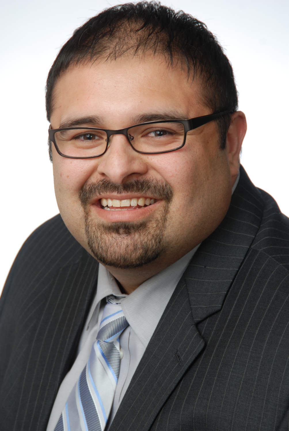 Picture of Dominic Martinez smiling in front of a light gray background