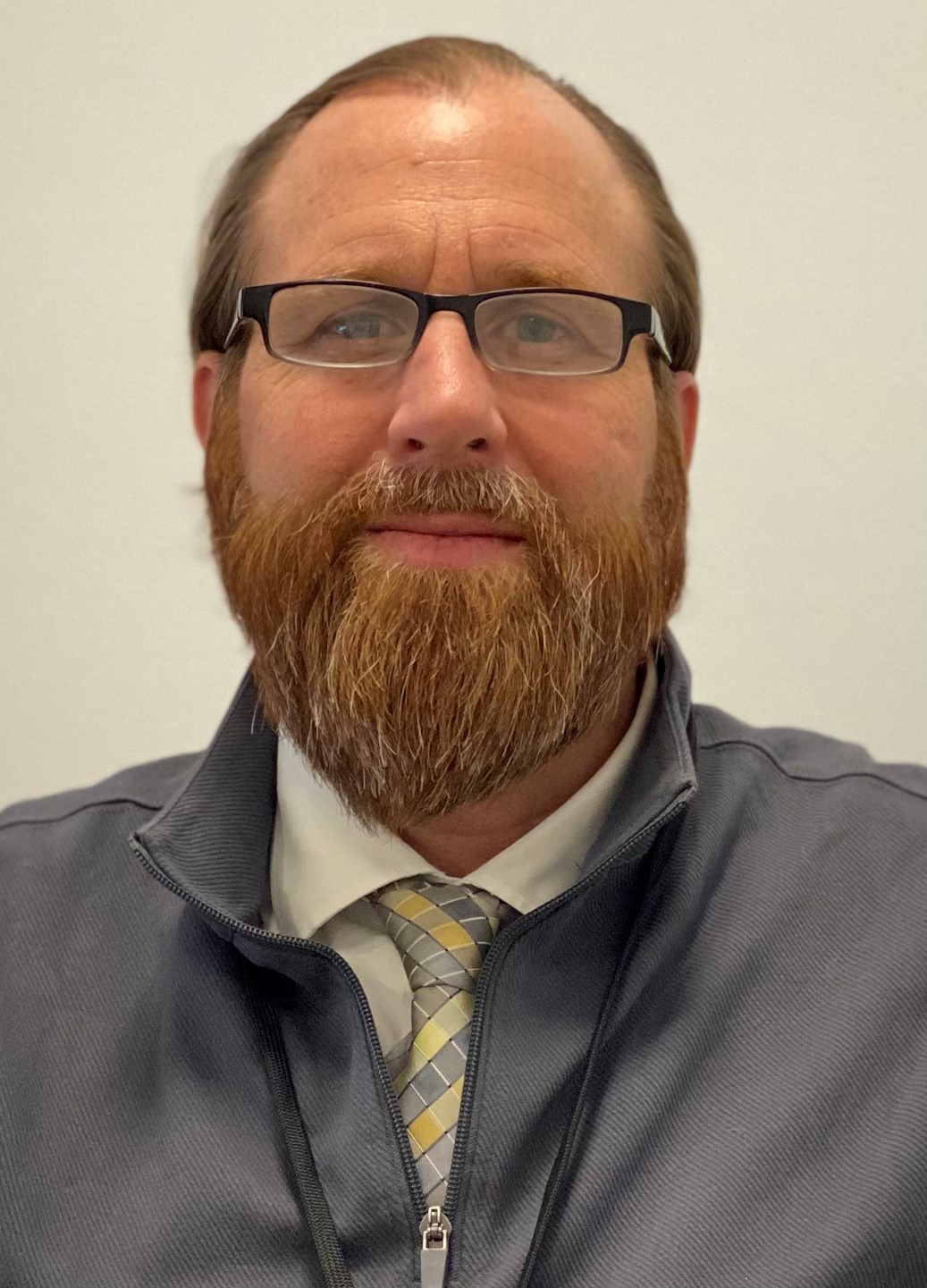 Mark smiling in front of a white background
