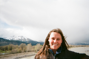 Woman smiling outside in front of a lake and mountain