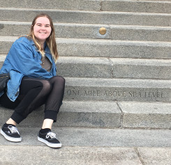 Woman sitting and smiling on the steps of the Colorado Statehouse at the 
