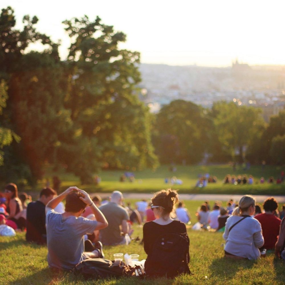 A group of people laying and playing in a sunny park.