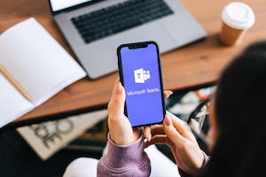 AdobeStock_408332490_Editorial_Use_Only Adobe stock pic of a person holding a cell phone in their hand showing the Microsoft Teams image