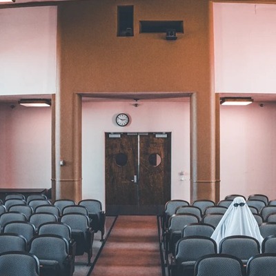 A ghost wearing sunglasses sits in one of the audience seats in the Bushnell Auditorium.