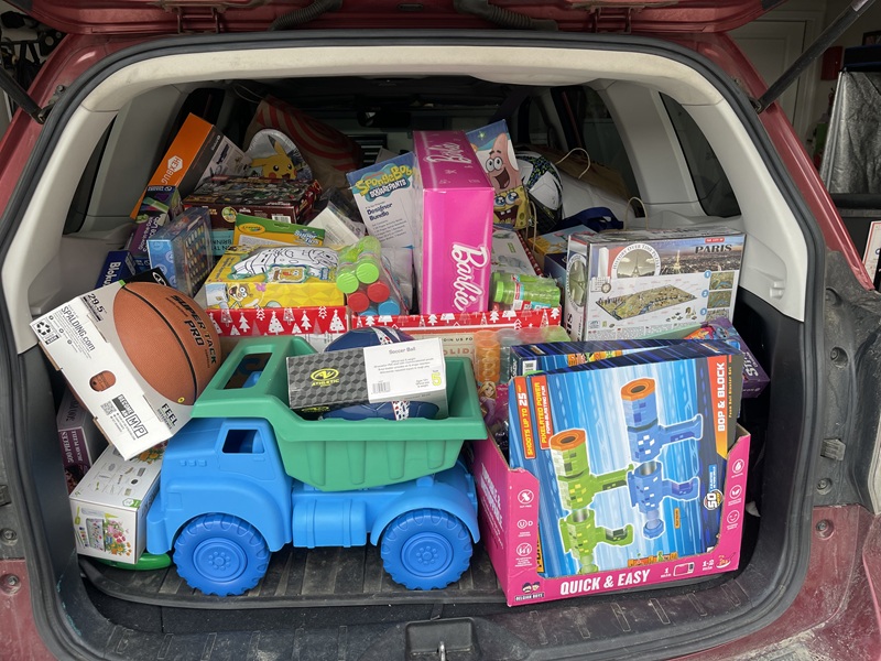 The back of a car with rear passenger seats folded down to accommodate bags and boxes of toys.