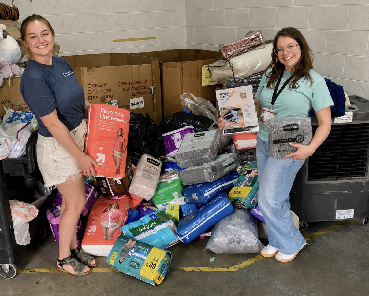 two women standing in front of collection bins overflowing with donated incontinence items