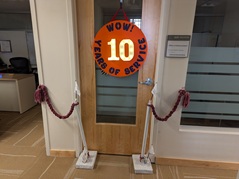 An office door has handmade stanchions and a light up sign that reads, 