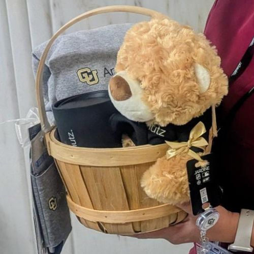 Prize basket featuring a teddy bear and mug and other CU Anschutz branded items.